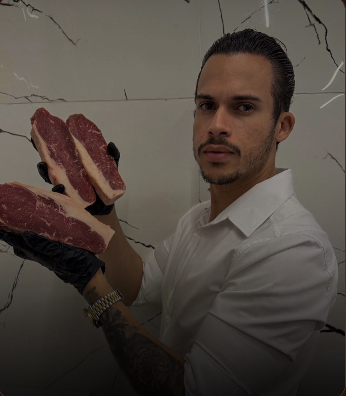 Wéricles Silva, açougueiro e dono de casa de carnes, segurando cortes de carne